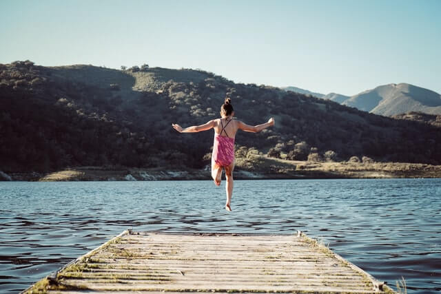 girl jumping into lake
